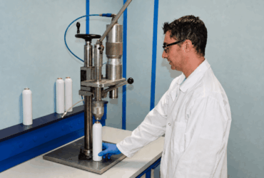 Technicien du LEREM contrôlant un contenant métallique avec des gants de laboratoire